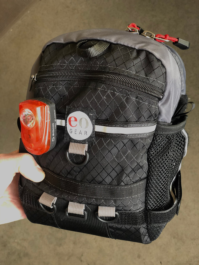 There is a hidden slot for a blinky tail light (to the left of the label), however, this bag tilts downward rendering if less effective. We recommend mounting lights on your seat stay instead.