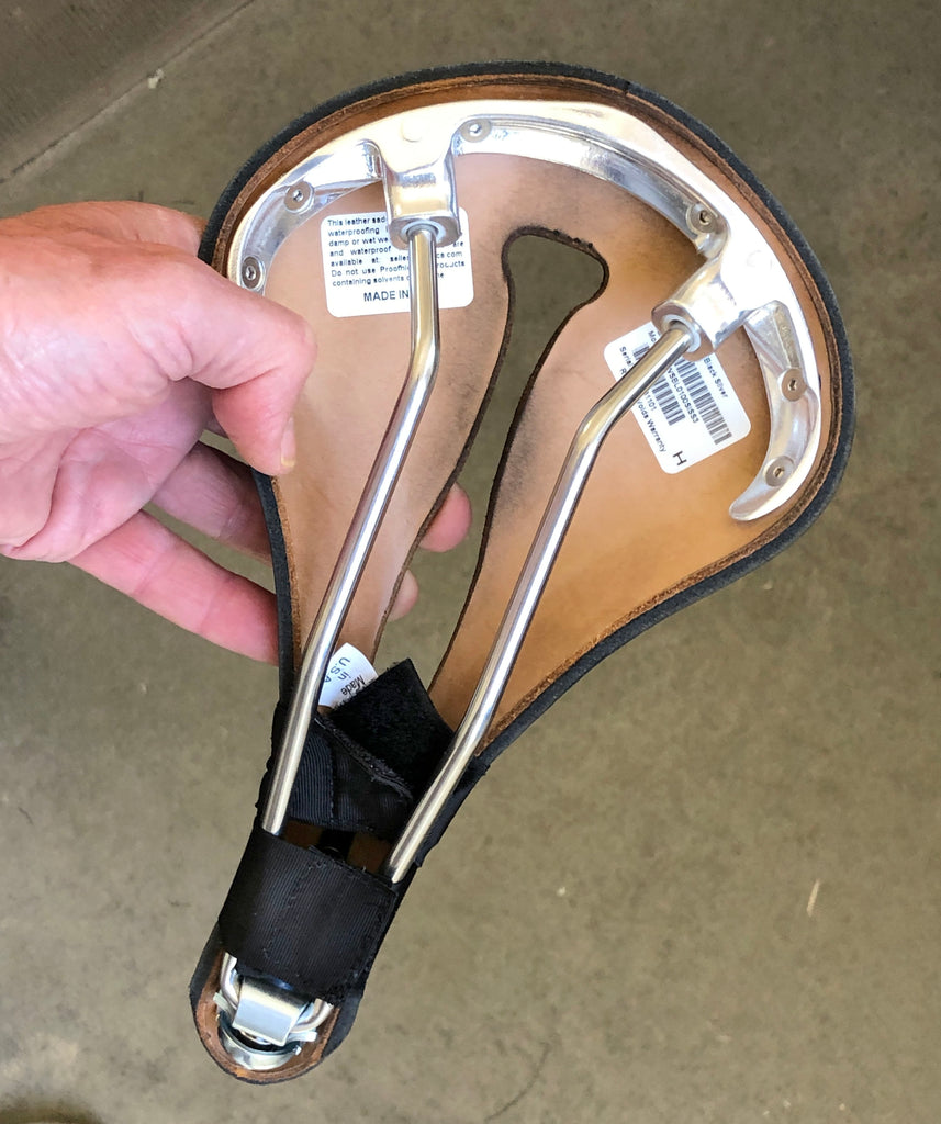 INSTRUCTIONS: The Made in USA label should be facing towards you and facing the rear of the saddle. Depending on your saddle model, the strap on the “nose” end can go either over or under the rails. If you are also using a compression strap, attach this one on first.
