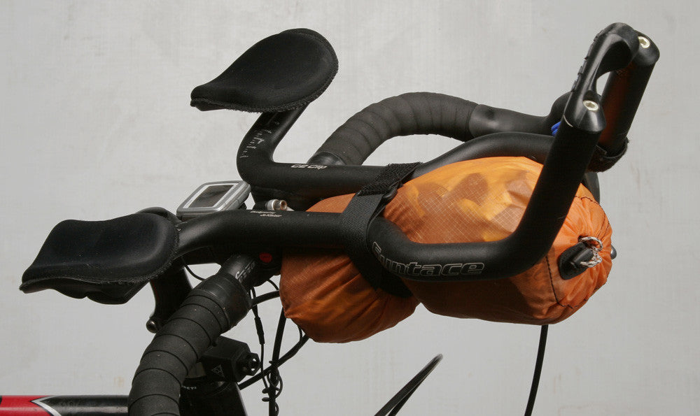 Single strap securing a 2L stuff sack to a pair of aerobars.