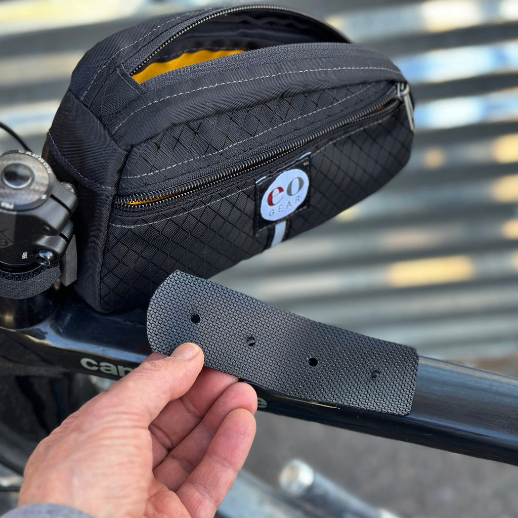 A rubber-like pad is provided. You will want to place it between the bag and your frame to prevent the grommets from scratching your frame.